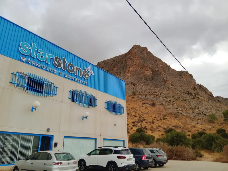Fachada de la nave de Starstone Mármoles y Granitos en La Aparecida, con el monte detrás
